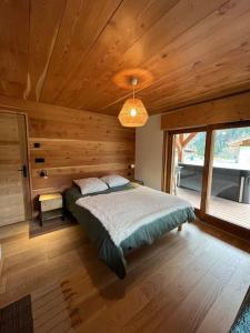 夏蒙尼-勃朗峰Chalet Le petit paradis - Chamonix-Mont-Blanc的卧室配有一张床铺,位于带木墙的房间内