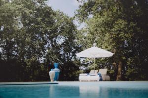 Bénesse-MaremneRiad Landais的一个带遮阳伞、椅子和桌子的游泳池