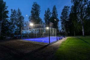 萨洛Saunamäki Resort - Lux Villa的一座玻璃房子,晚上设有网球场