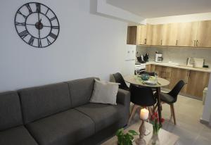 希俄斯Central Luxury Flat 2的客厅配有沙发和墙上的时钟