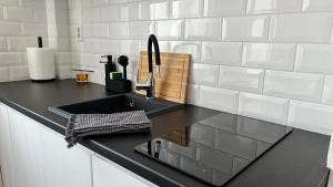 斯维诺乌伊希切Apartamenty Przy Deptaku的厨房配有黑色水槽和白色瓷砖
