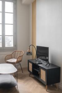 蒙彼利埃Appartement 2 pièces Montpellier centre的客厅配有电视和桌椅
