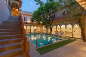 古尔冈Stay Vista at Khohar Haveli - 18th Century Palace with Modern Amenities的一座庭院,旁边设有游泳池和楼梯