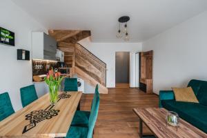 新塔尔格Gorczański Resort Domek w Górach Sauna Jacuzzi的用餐室以及带木桌和绿色椅子的客厅。