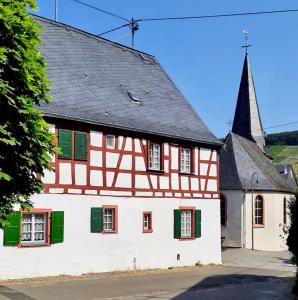贝尔恩卡斯特尔-库斯Ferienhaus Wagner的一座带绿色百叶窗和教堂的古老房子