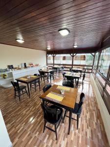 纳塔尔Pousada Recanto de Ponta Negra的餐厅设有木桌、椅子和窗户。