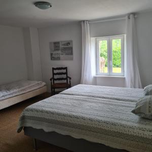 昂比La Balnière Normande的一间卧室设有一张床、一个窗口和一把椅子