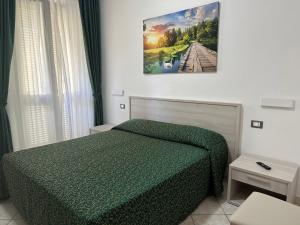 阿祖罗港Hotel Barbarossa的卧室配有绿色的床,墙上挂着一幅画