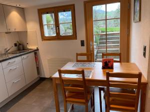 格施塔德Alpenchalet Spiher Gstaad Ferienwohnung im Parterre的厨房配有木桌、椅子、桌子和窗户。