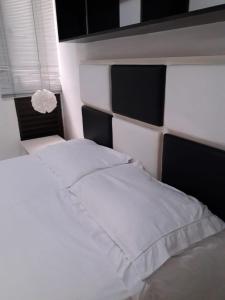 巴西利亚Kit no Lago Norte CA 02的一张白色的床,上面有黑白床头板