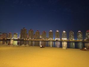 多哈Luxury Sea View Apartment with Amazing Amenities at Pearl Qatar的城市天际线,夜晚有海滩和建筑