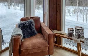 赫讷福斯4 Bedroom Gorgeous Home In Hnefoss的靠窗边的棕色皮椅和毛绒枕头