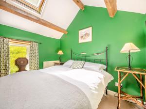 Askham磨坊谷仓度假屋的绿色卧室,配有床和绿色的墙壁