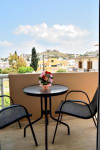 阿彻奇洛斯ADONIOS APARTMENTS的阳台上的桌子,两把椅子和鲜花