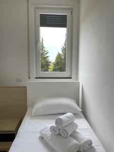 地拉那Kino Apartment的卧室配有带2条毛巾的窗户,位于床上