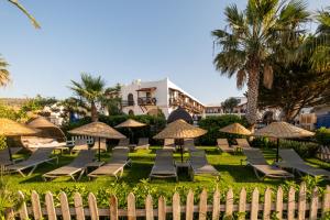 比泰兹Costa Bitezhan Hotel - All Inclusive的一组草坪椅和遮阳伞位于度假村前