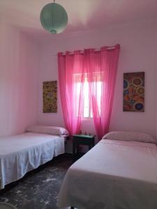 奇皮奥纳Villa Antonia的客房设有两张床和一个带粉红色窗帘的窗户。