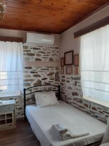 桑加拉达Ξυλοπετρα / Wood & stone house的石墙房间内的一张床位