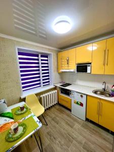卡拉甘达Яркая квартира в стиле Поп Арт в центре города Караганда的厨房配有黄色橱柜、桌子和水槽