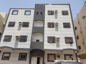 麦地那شقة مفروشة رقم 1 تبعد عن الحرم النبوي الشريف 3 كم的一座高大的白色建筑,设有铁窗