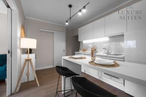 塞萨洛尼基Nephele, The Luxury Suites的厨房配有白色橱柜和带凳子的台面