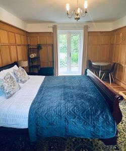 巴顿尼德伍的Canalside Cottage的一间卧室配有一张带蓝色棉被的床和窗户。