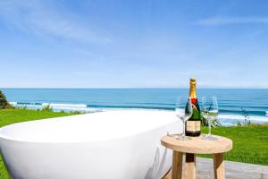 MokauMOKAU BEACH HOUSE的浴缸配有1瓶香槟和2杯酒