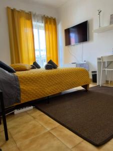 萨卡文Nosso Aconchego的黄色窗帘和电视的房间里的一个床位