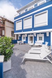 乌迪亚莱斯堡VILLA MARTA - Apartamentos céntricos junto al mar的一座蓝色的建筑,前面设有桌椅