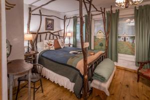 格伦罗斯Country Woods Inn的一间卧室配有一张天蓬床和一张桌子及椅子