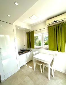 杜布罗夫尼克罗马拉公寓的厨房配有白色的桌子和绿色的窗帘