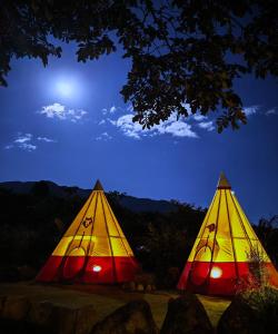 奥克萨潘帕BIOSFERA LODGE GLAMPING tipi 2 personas的两个颜色的帐篷,晚上在田野里