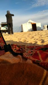 Az ZabūEgypt white and black desert with Camping的站在海滩上帐篷旁的人