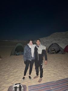 Az ZabūEgypt white and black desert with Camping的男人和女人晚上站在海滩上