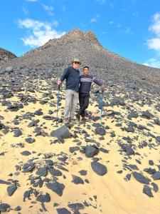 Az ZabūEgypt white and black desert with Camping的两个人站在海滩上,岩石堆成