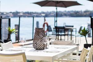 悉尼Newly Reburbished Sydney Harbourfront Boathouse Escape的酒杯桌子和花瓶