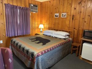圣伊尼亚斯Cedars Motel的卧室配有一张床铺,位于带木墙的房间内