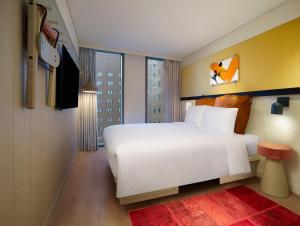 首尔Moxy Seoul Myeongdong的卧室设有白色的床和大窗户