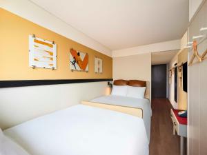 首尔Moxy Seoul Myeongdong的酒店客房,设有两张床和黄色的墙壁