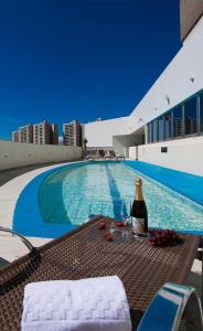 巴西利亚Promoção - Flat em Brasília的游泳池畔的桌子上摆放着一瓶葡萄酒