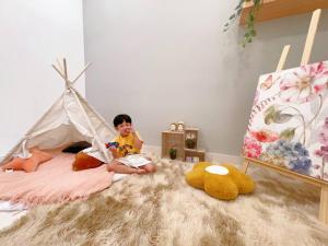 马西MONIC STAYCATION #Green Haven near Senibong&Regency的坐在床上的小孩和锥形帐篷