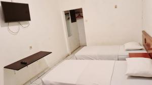 棉兰Acirasa Homestay Medan的配有两张床铺的客房,墙上配有电视