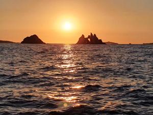 波克罗勒岛Porquerolles - Nuit insolite à bord du Défi Fou的海上的日落,岩石在水中