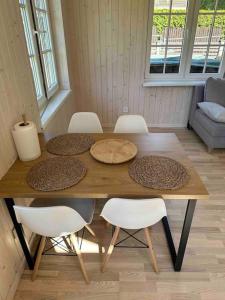 尤尔马拉Melluži tiny house的一张带白色椅子的木桌和一张带盘子的桌子