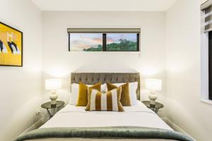 奥克兰Pristine Modern Central Home - Netflix - Heatpump的一间卧室配有一张带黄色枕头的床和一扇窗户