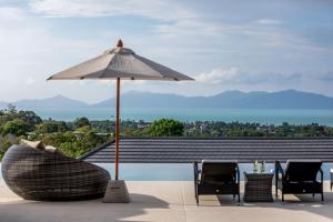 苏梅岛Villa Mandra - Beautiful 4 Bedroom Luxury Pool Villa KBR2的庭院配有桌子、遮阳伞和椅子