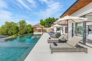 苏梅岛Villa Mandra - Beautiful 4 Bedroom Luxury Pool Villa KBR2的房屋旁设有带椅子和遮阳伞的无边泳池