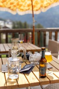 阿罗萨Pension Arosa - Self Check-In的一张木桌,配有一瓶啤酒和玻璃杯