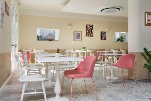 里米尼Pan di Zenzero的一间设有白色桌子和红色椅子的餐厅