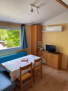 萨尔拉拉卡内达Joli Mobil-home climatisé entièrement équipé, sauf draps en option, pour 4 adultes au maximum avec possibilité de 2 enfants en plus的小房间设有桌子和窗户